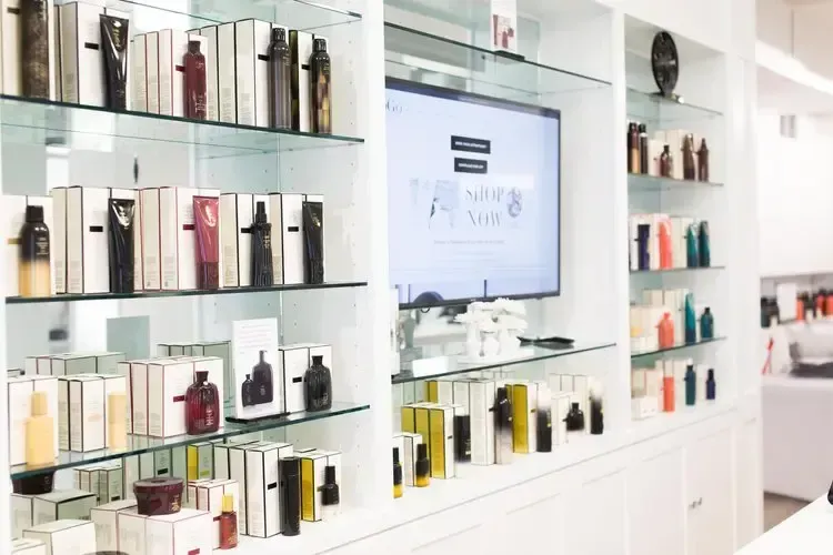 Shelves in a brightly lit beauty shop with products, and a TV screen in the center.