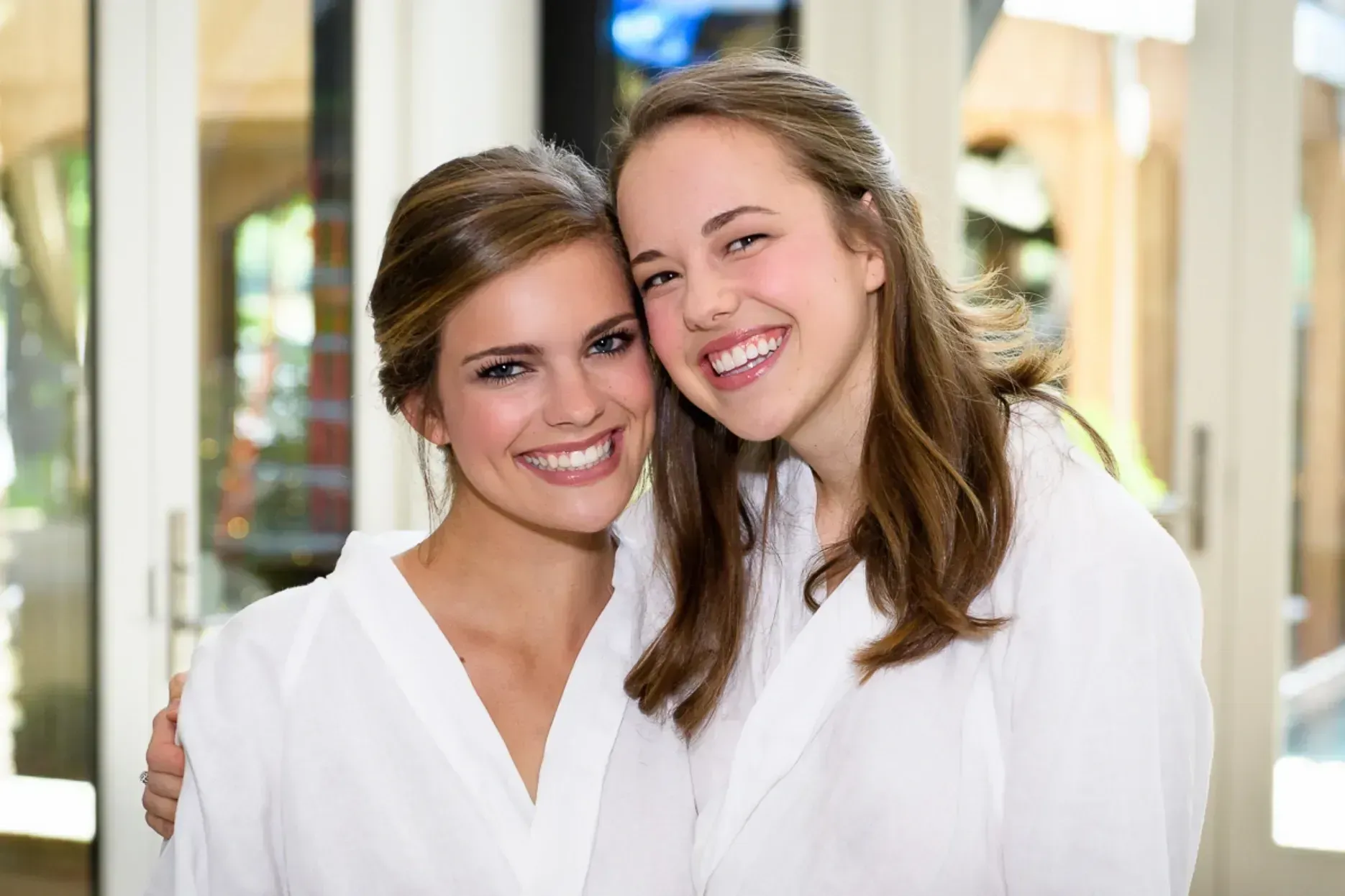 Two smiling women in white robes pose for a photo.