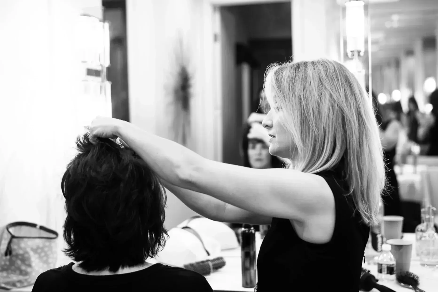 Hair stylist working on a person's hair in a brightly lit room.
