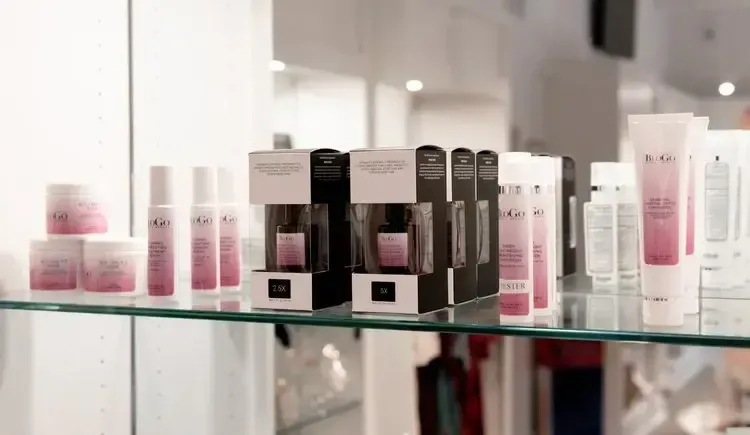 Shelf display of skincare products, featuring various pink and white containers.