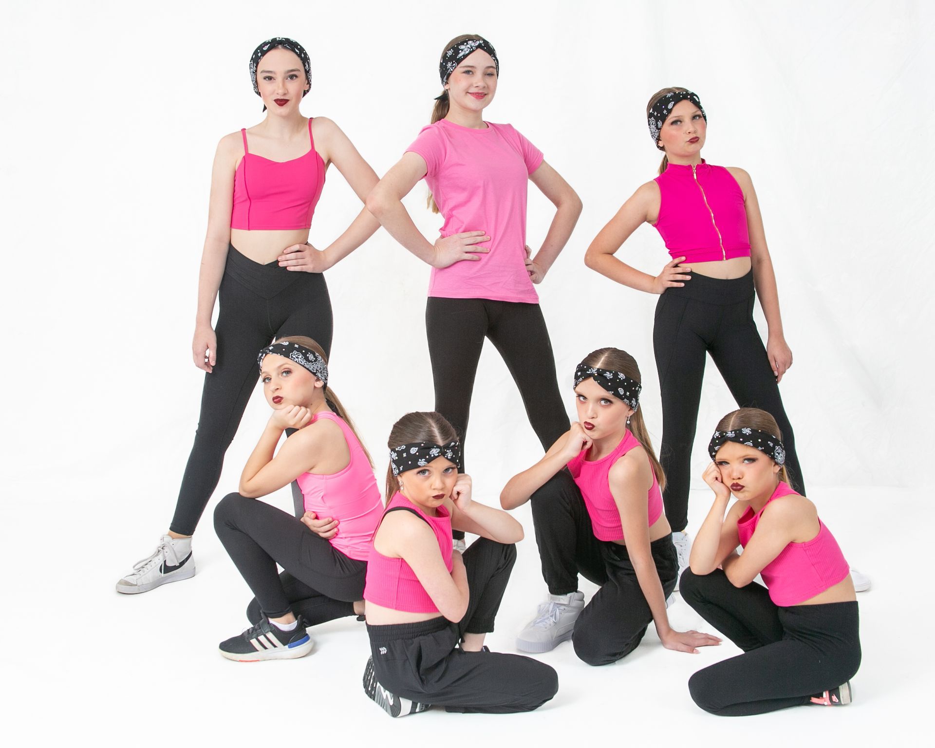 A group of young girls wearing pink tops and black pants are posing for a picture.