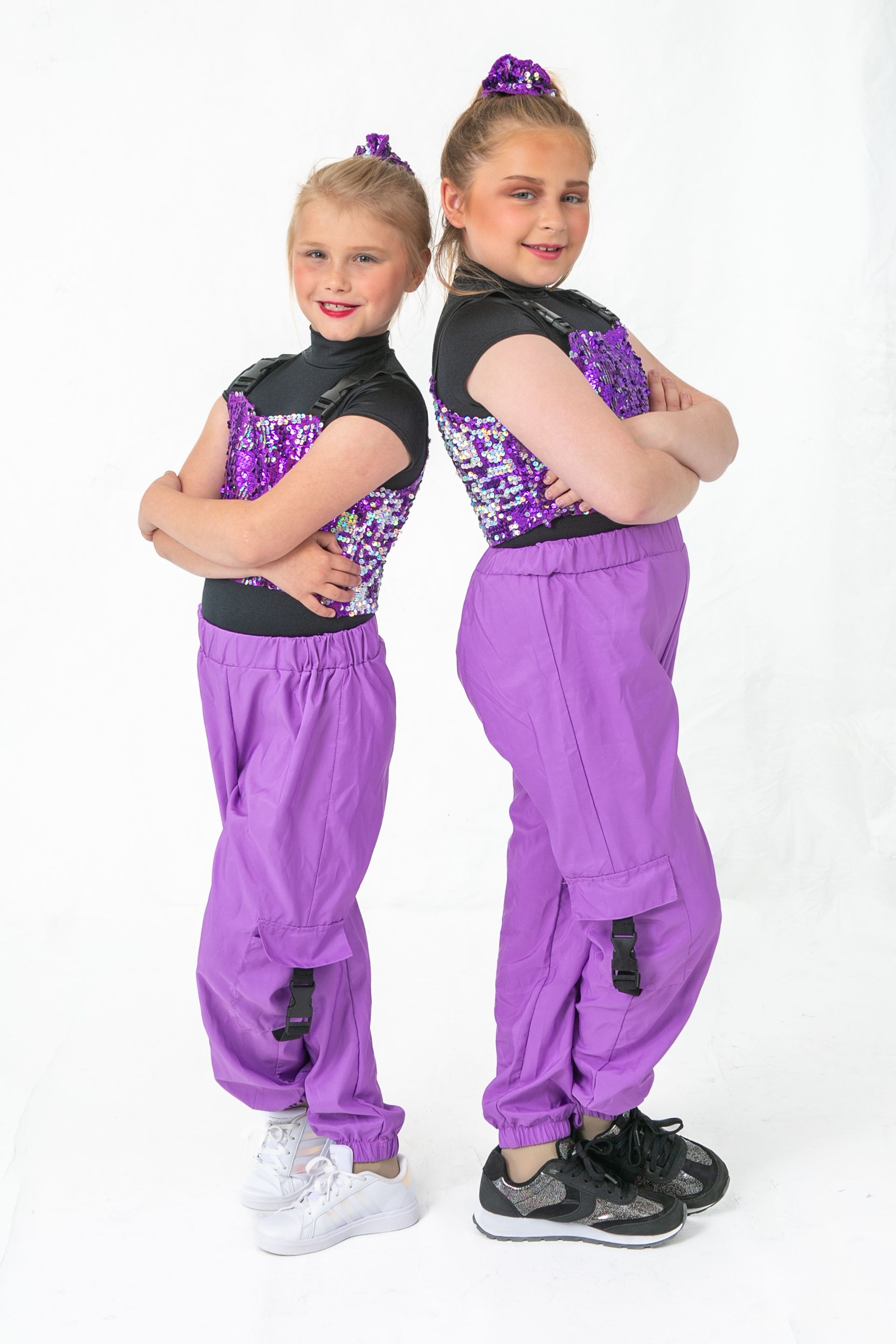 Two young girls are standing next to each other with their arms crossed.