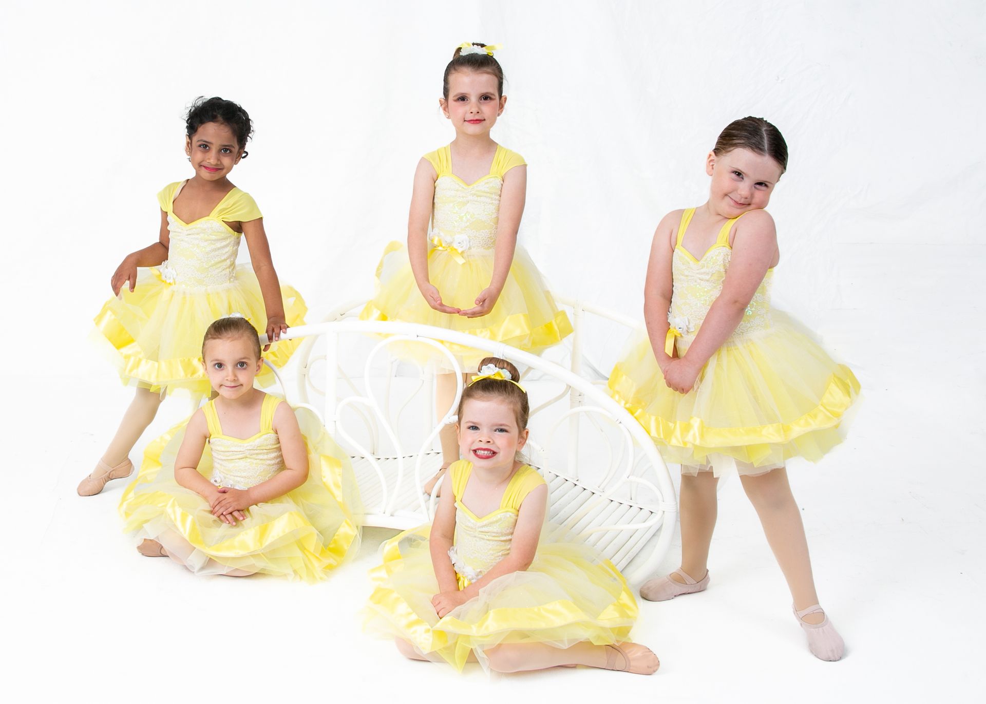 A group of young girls in yellow dresses are posing for a picture.