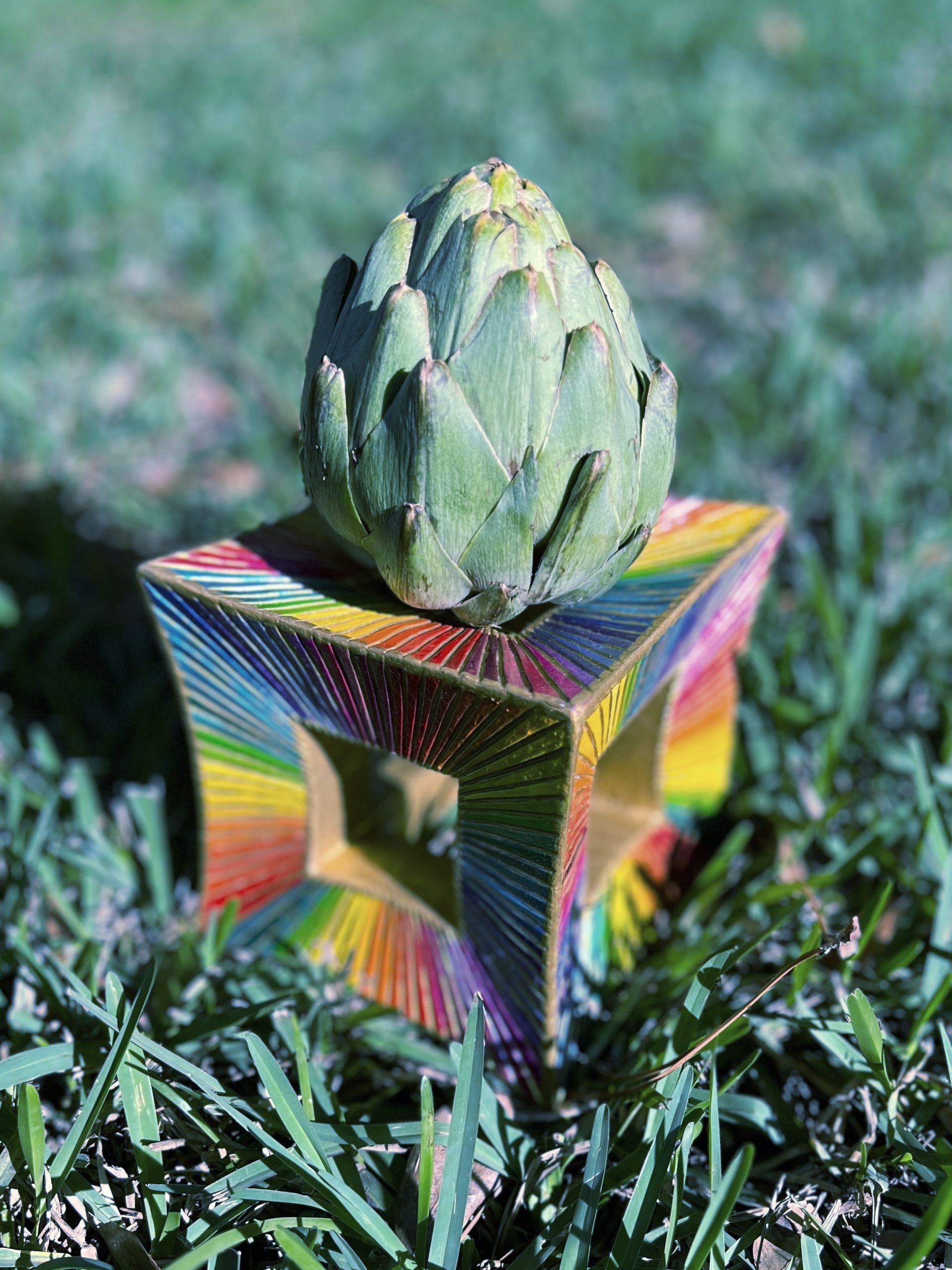 photo of an artichoke in a rainbow stand, representing uniqueness and creativity
