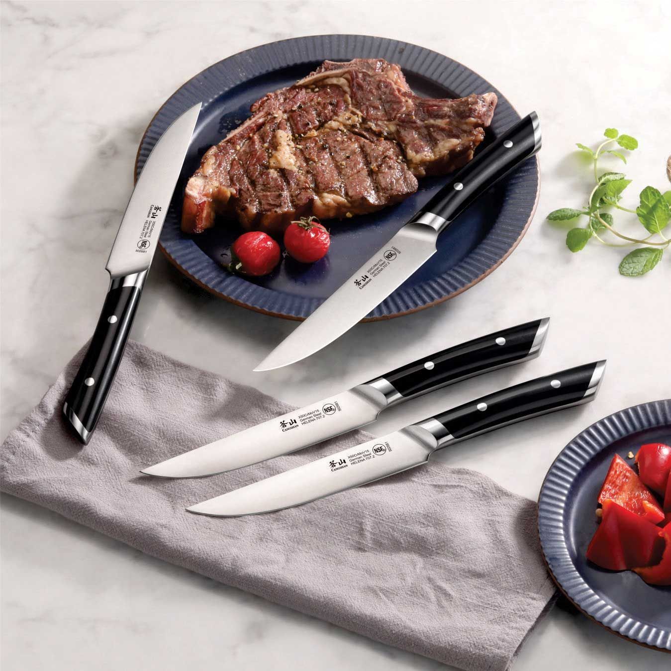 A steak is on a plate next to three knives.