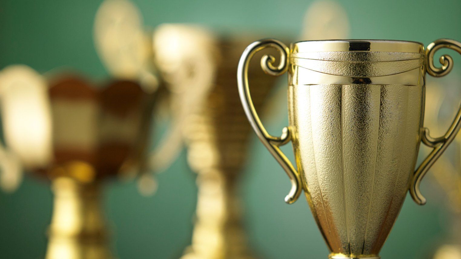 A group of gold trophies are lined up in a row.
