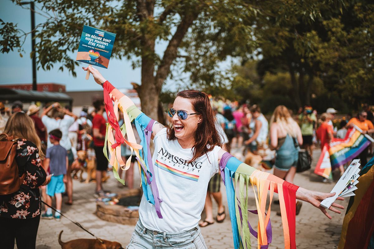 A woman is holding a book in her hand in front of a crowd of people.