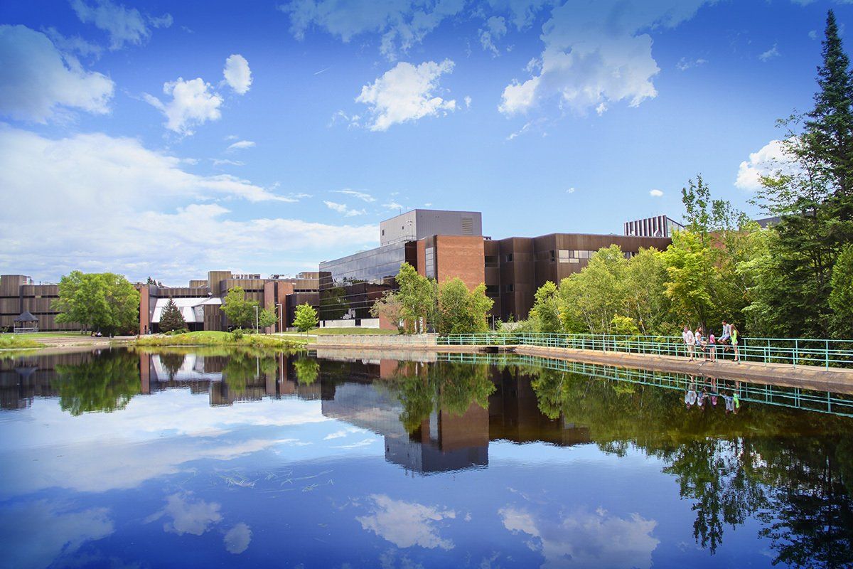 A large building is reflected in the water of a lake.
