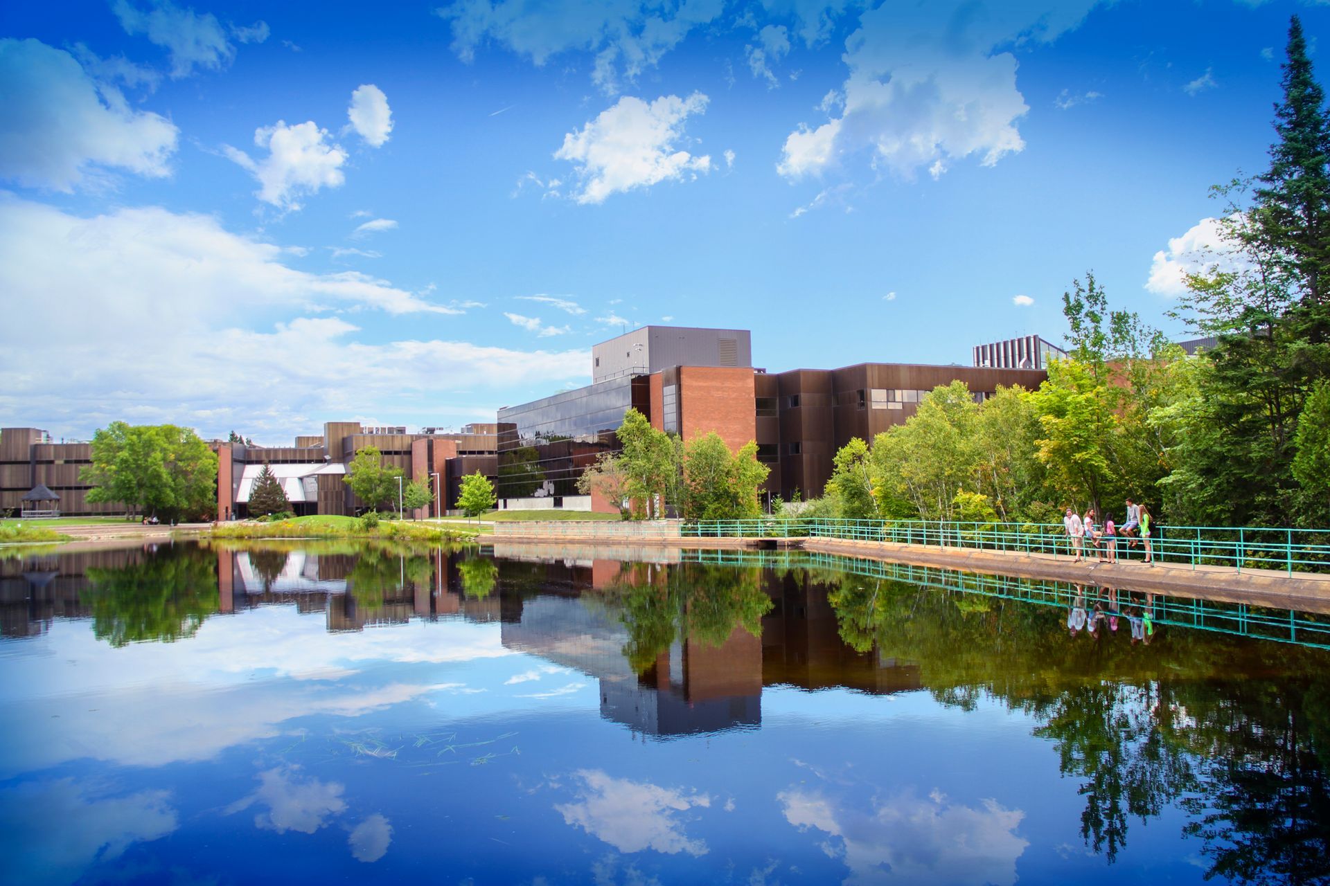 A large building is reflected in a body of water surrounded by trees.