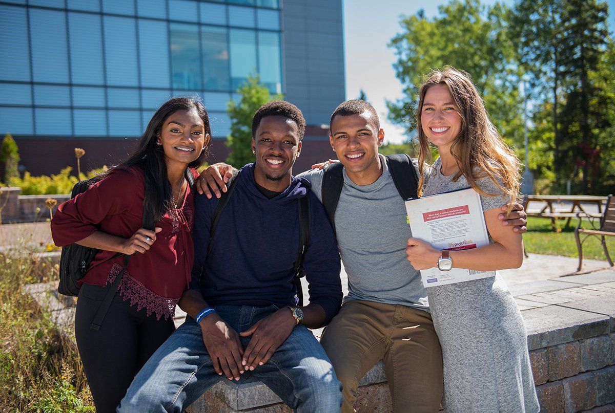 A group of young people are posing for a picture in front of a building.