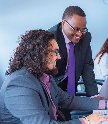 Two men in suits and ties are looking at a laptop computer.