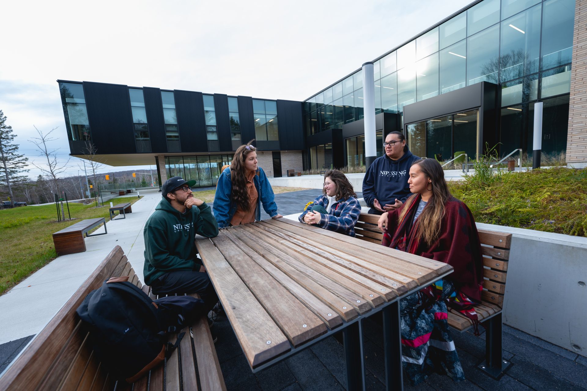 A group of people are sitting at a table outside of a building.