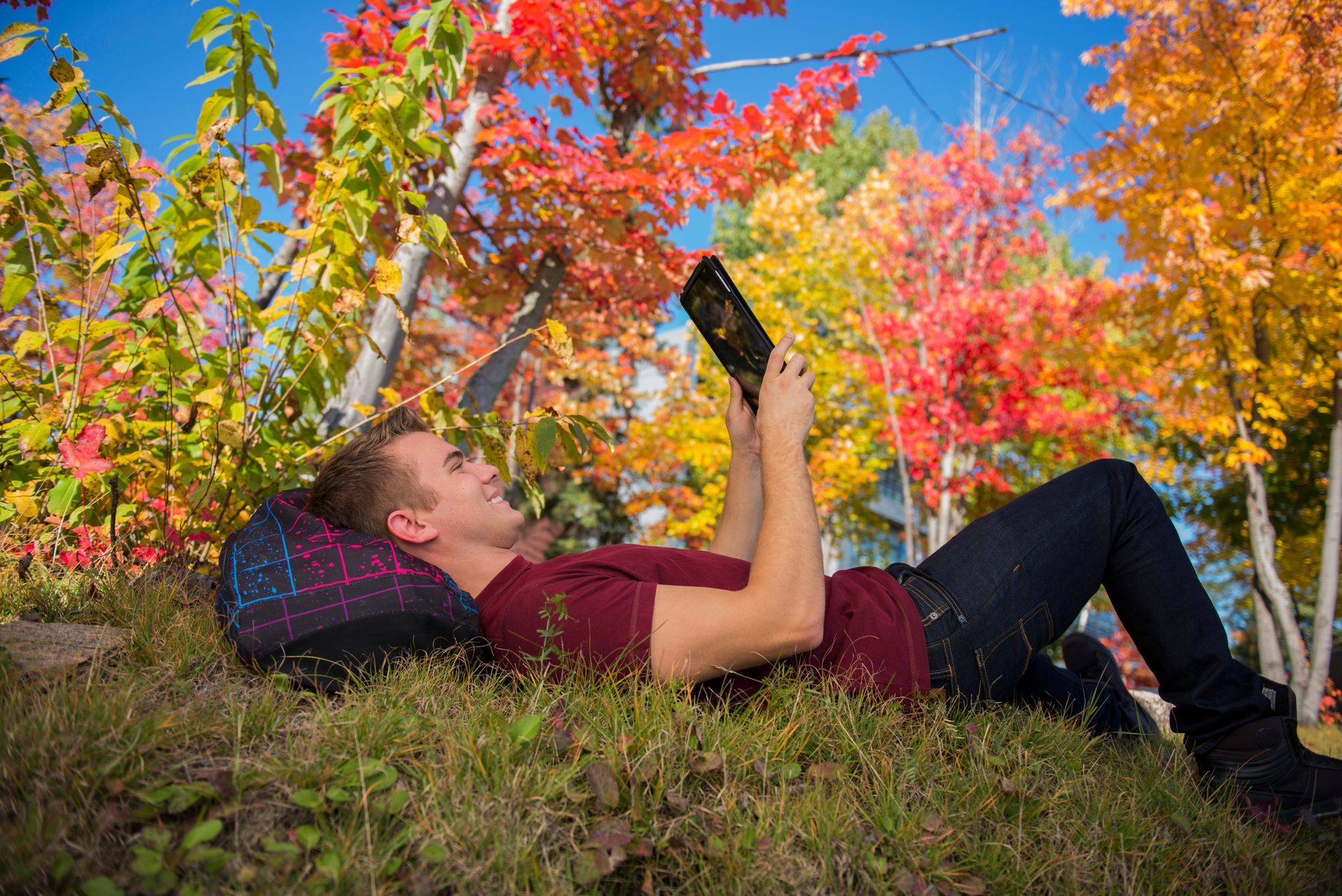 A man is laying on the ground reading a book.