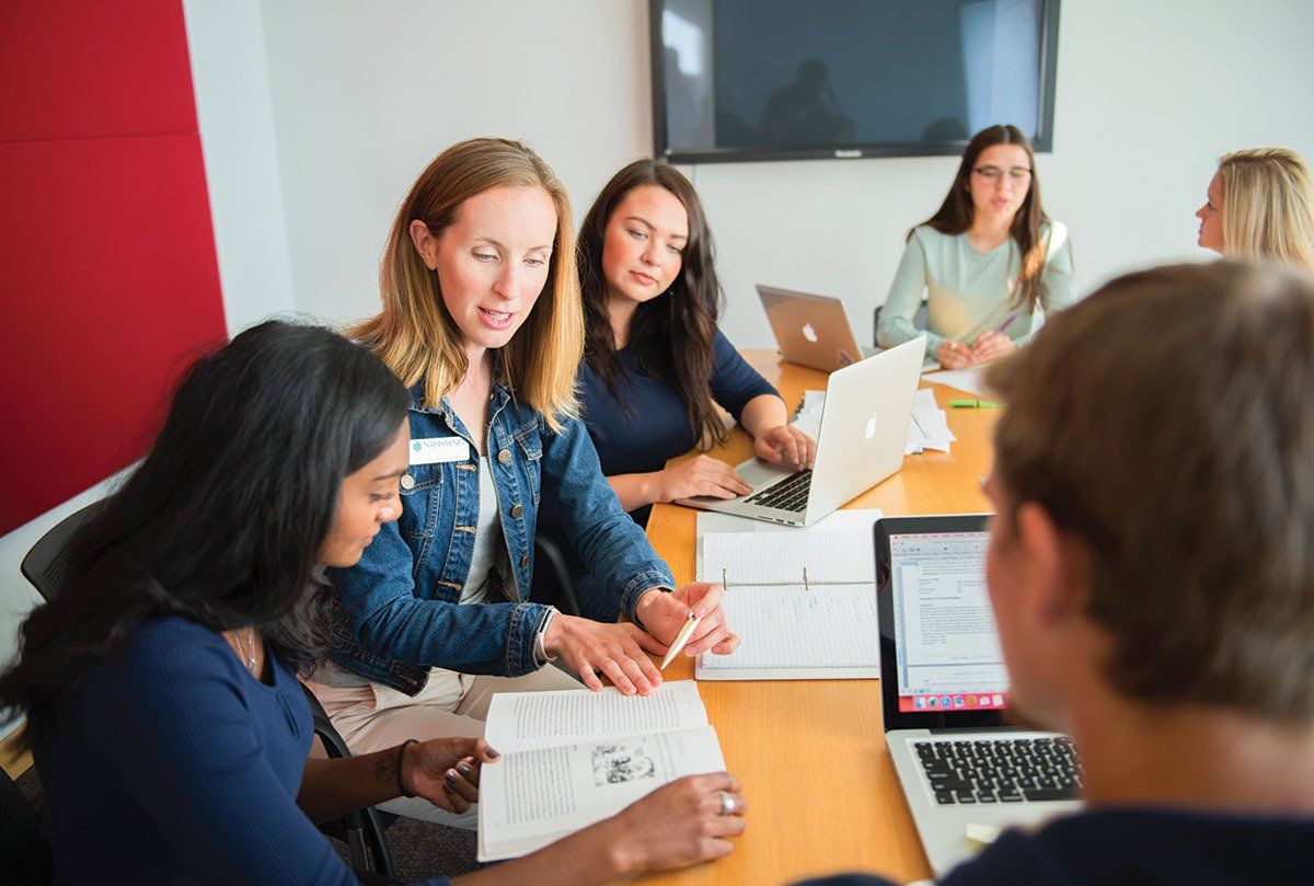 A group of people are sitting around a table with laptops.