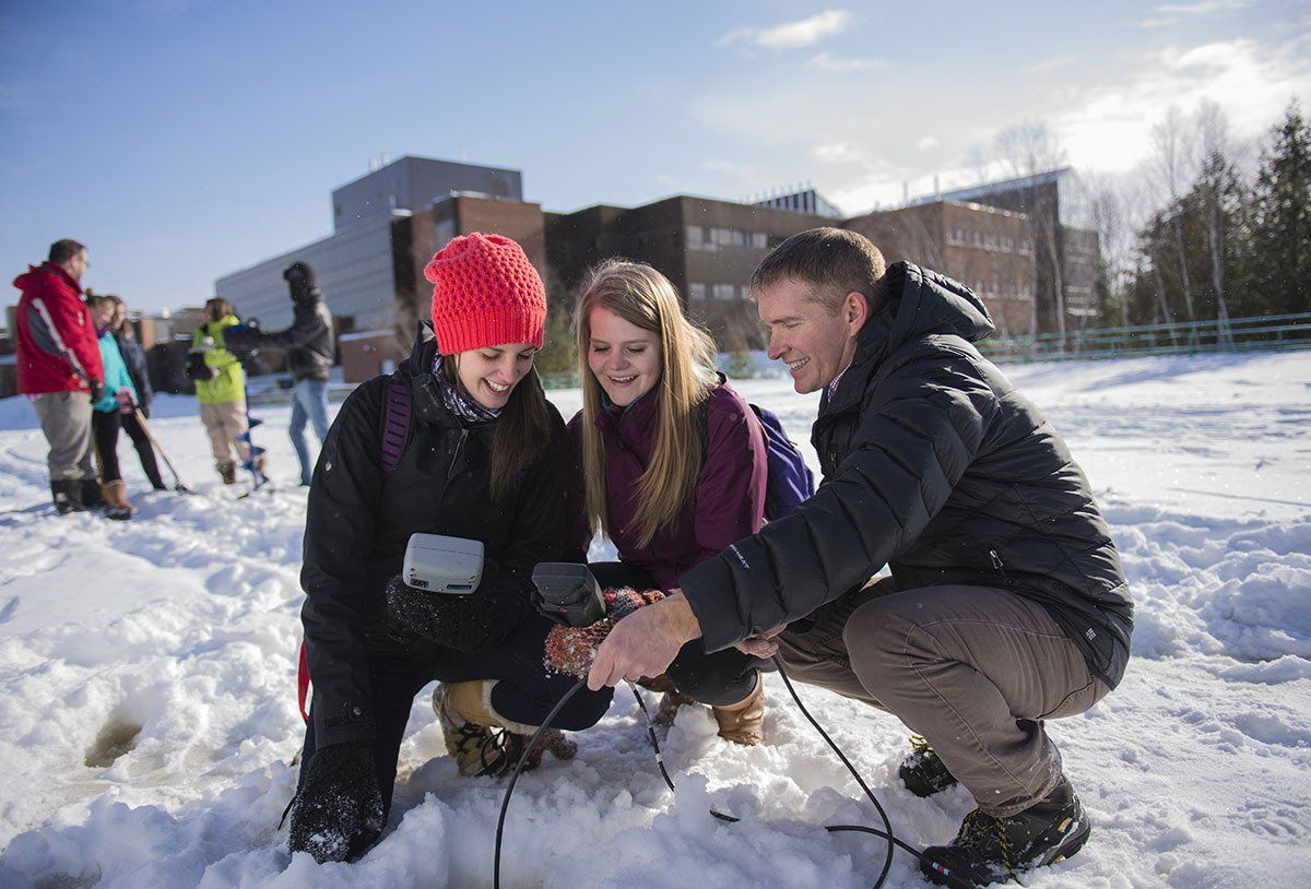A group of people are kneeling in the snow looking at something.