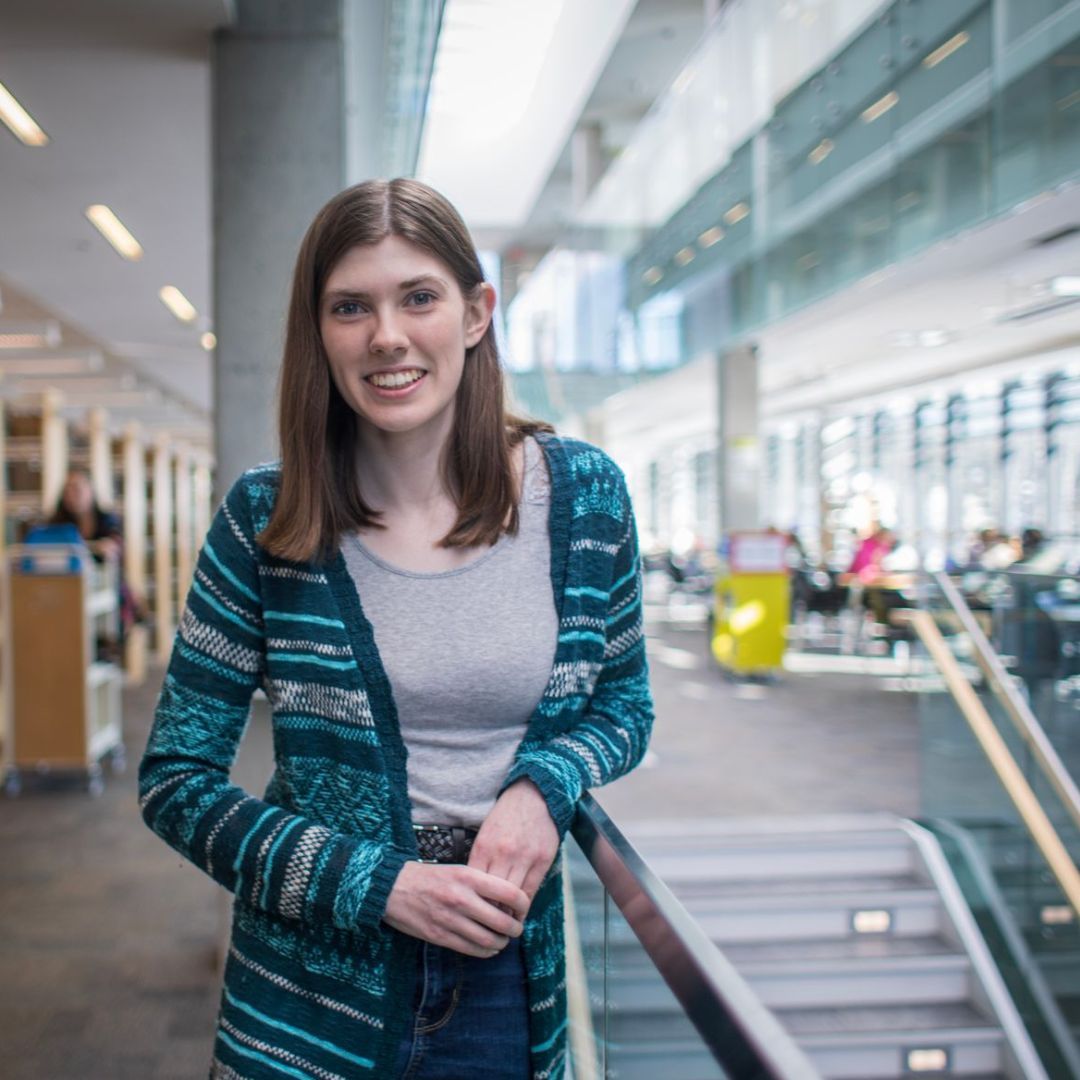 a student posing on the ledge of the library 