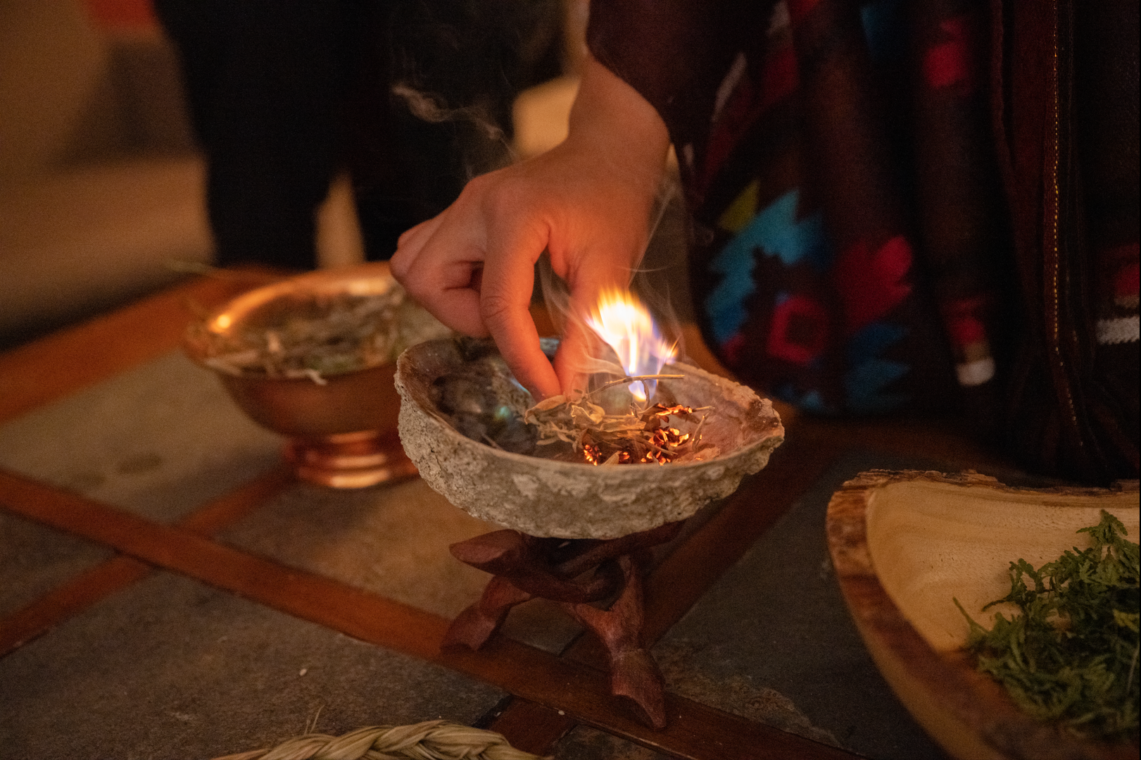 A person is lighting a candle in a shell on a table.