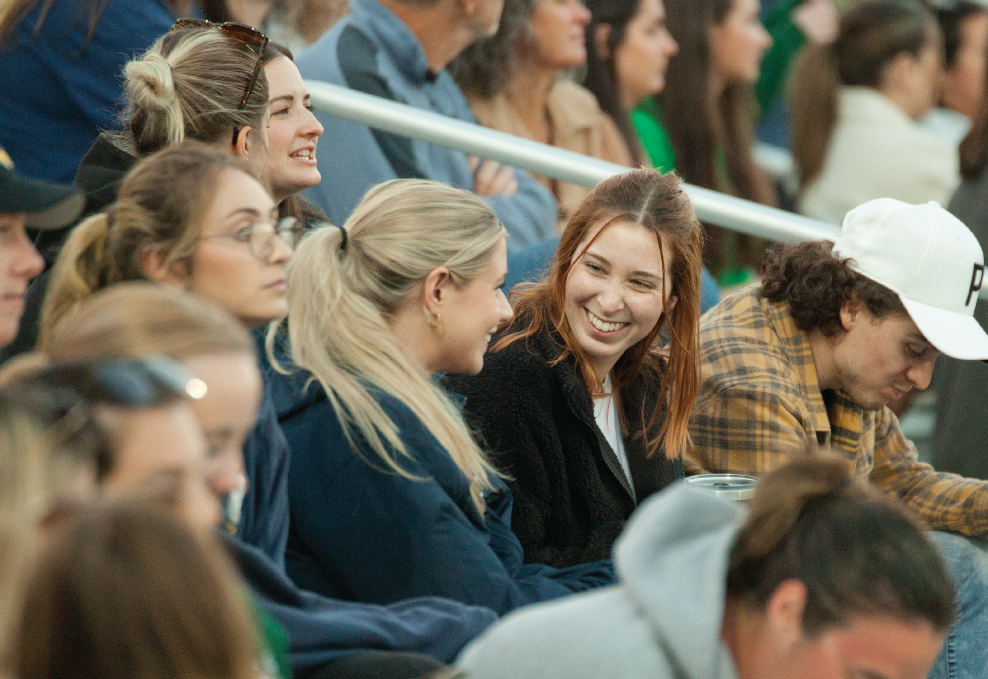 2 students talking and smiling within a group of people