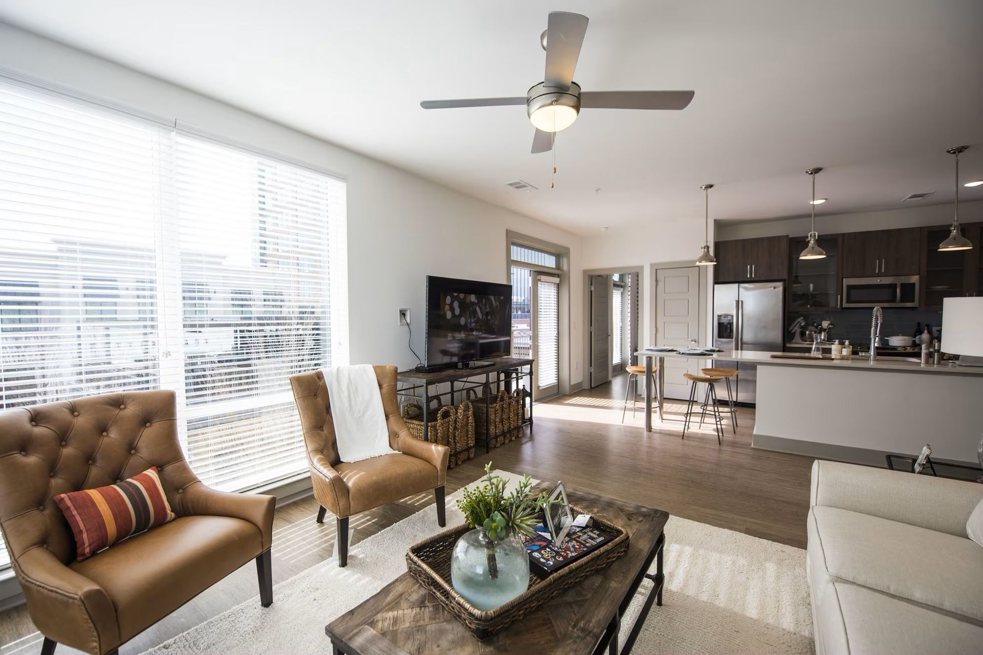 Living room with leather chairs, a coffee table, and kitchen in the background.