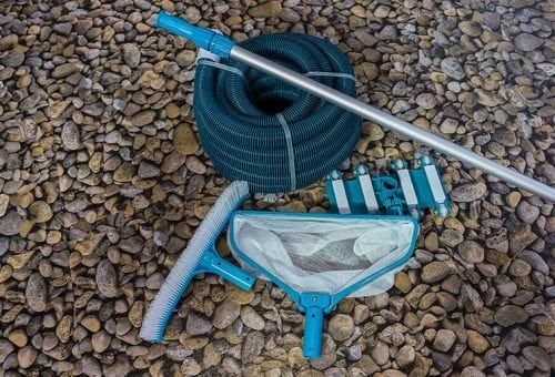 A Pool Cleaning Kit is Sitting on Top of a Pile of Rocks — Poolside Noosa in Noosaville, QLD