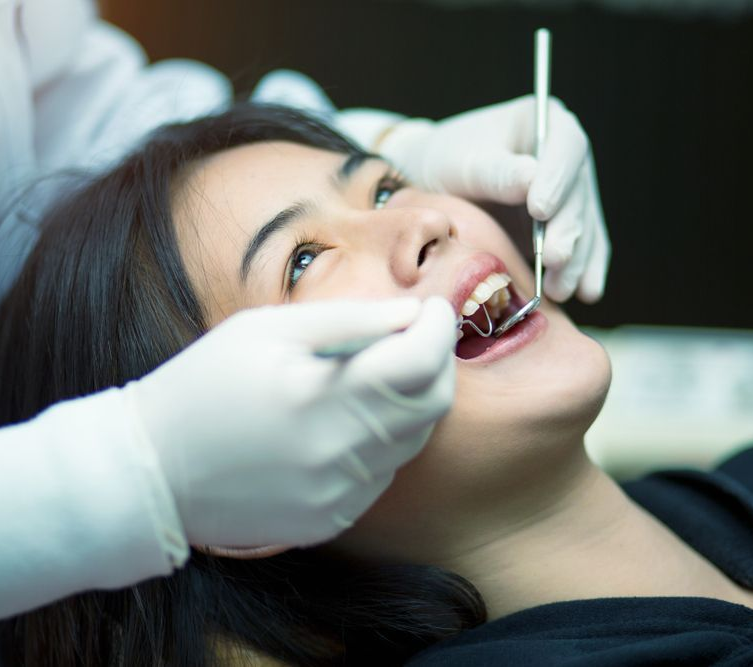 A person having a dental examination; dentist using tools to check teeth.