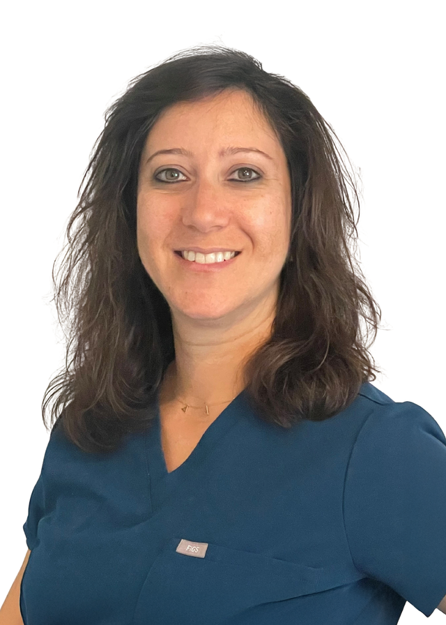 Woman in teal scrubs smiles, looking at the viewer.