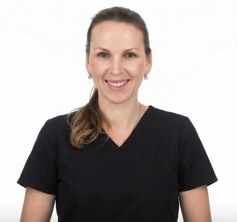 Woman wearing glasses and black scrubs smiles.
