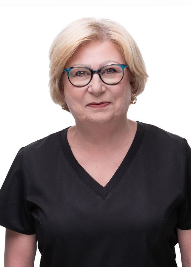 Woman with blonde hair wearing glasses and black top, smiling.