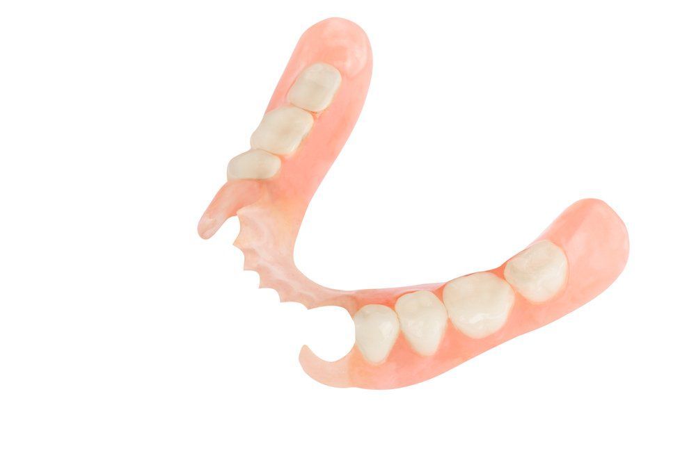 Partial dental prosthetic, pink with white teeth, isolated on white background.