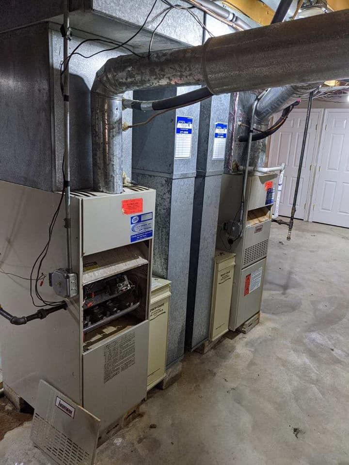 A couple of furnaces sitting next to each other in a basement.