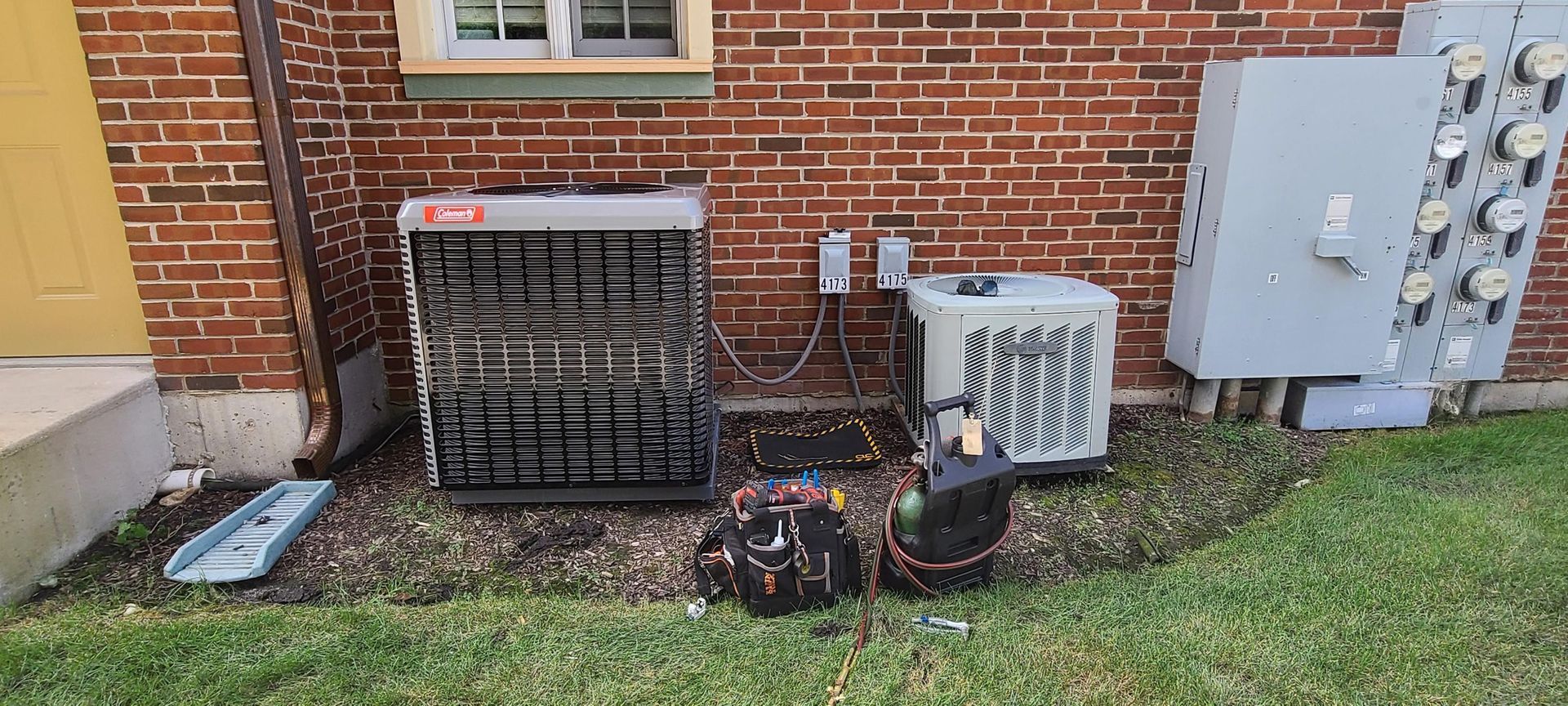 A couple of air conditioners are sitting on the side of a brick building.