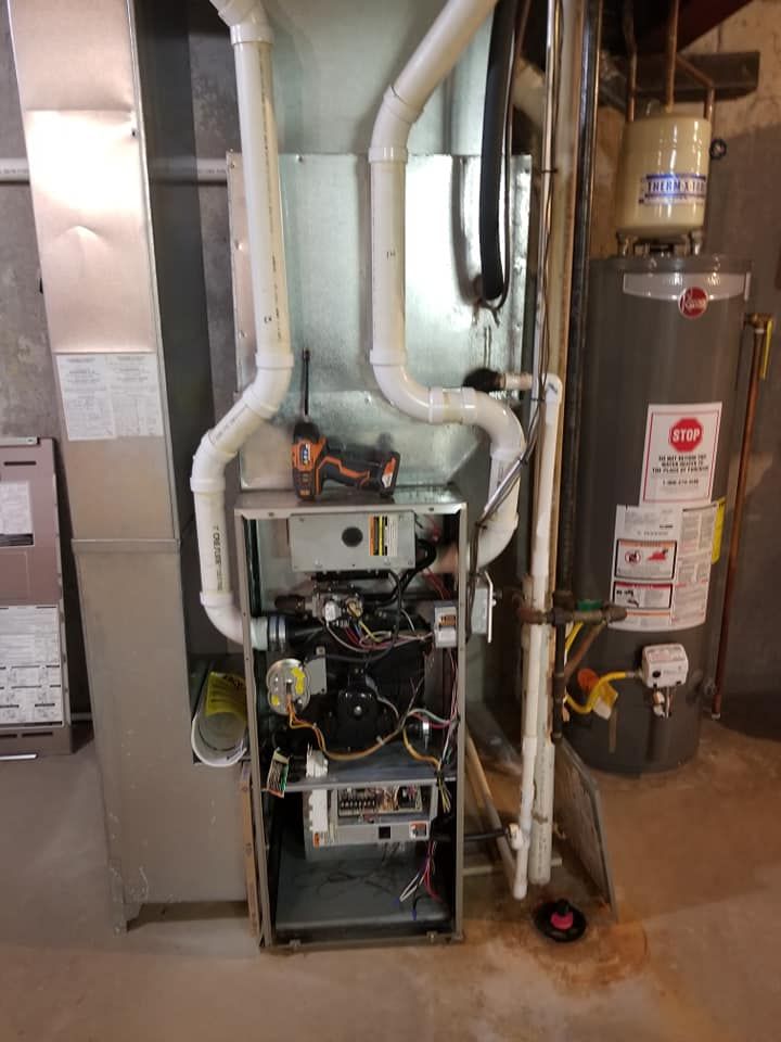 A gas heater is sitting in a basement next to a water heater.