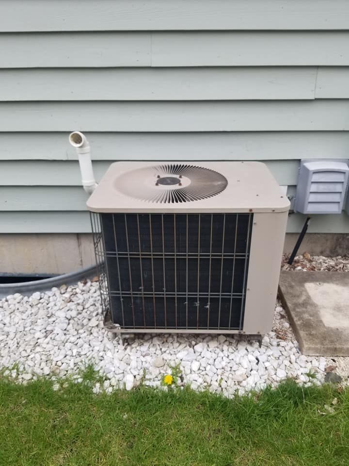 An air conditioner is sitting on the side of a house.