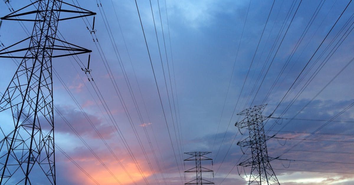 A row of power lines against a cloudy sky at sunset.