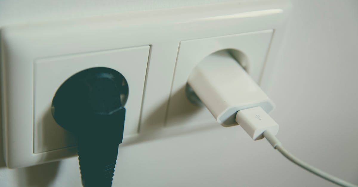 A black plug is plugged into a white electrical outlet.