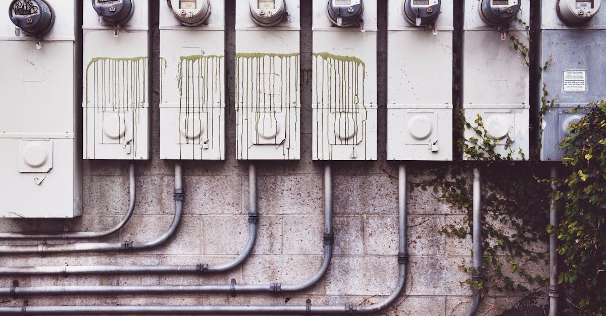 A row of electrical boxes and pipes on a wall.