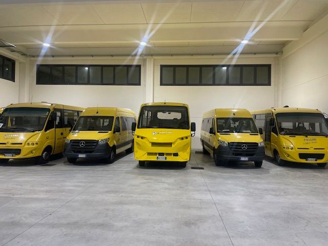 Cinque scuolabus gialli parcheggiati all'interno di un garage ben illuminato.