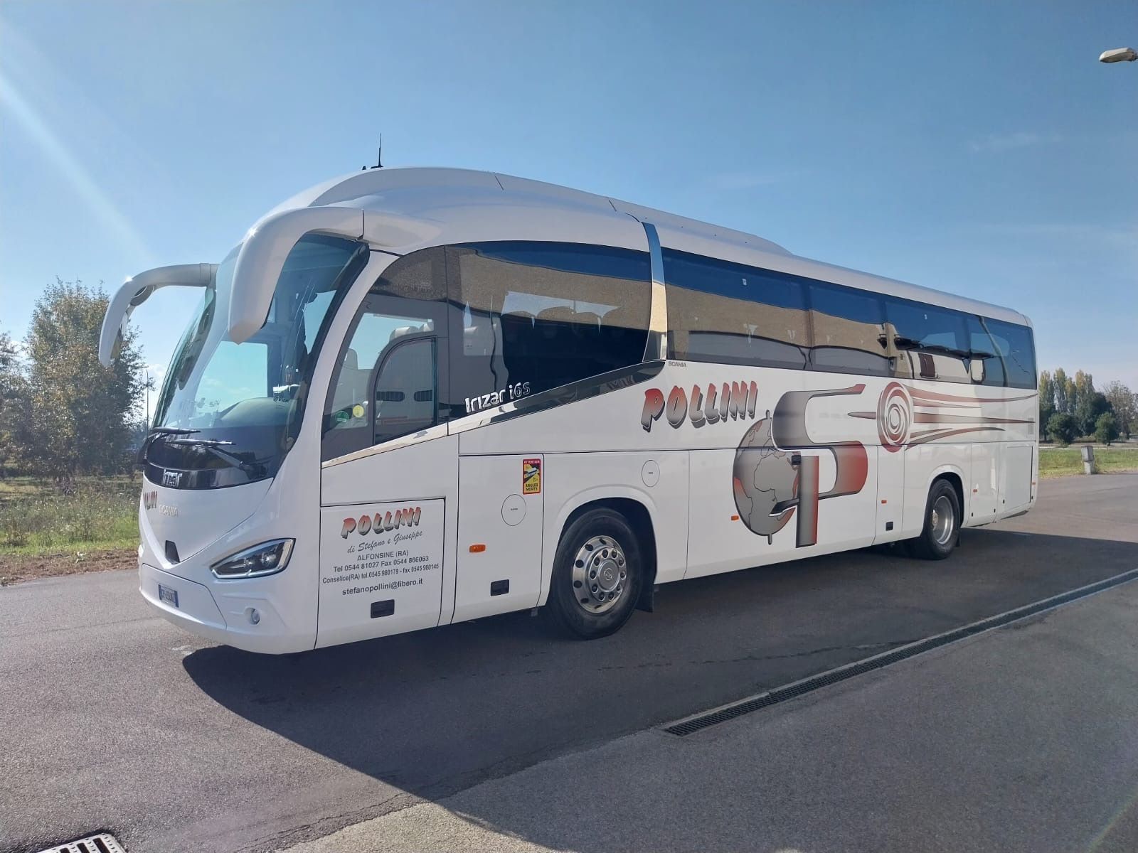 Un autobus bianco della Pollini parcheggiato all'aperto in una giornata di sole. La porta d'ingresso è aperta.