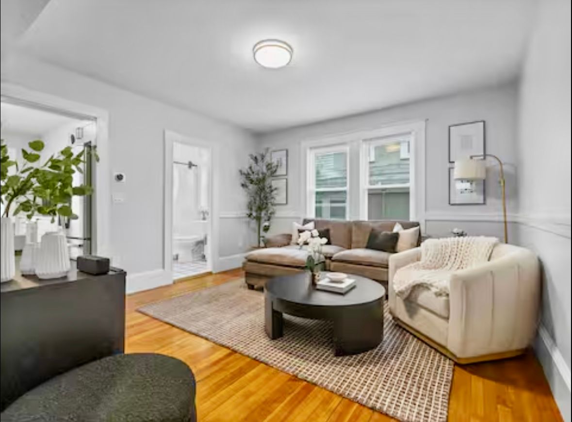 Living room with brown sectional sofa, beige armchair, dark coffee table, and area rug.