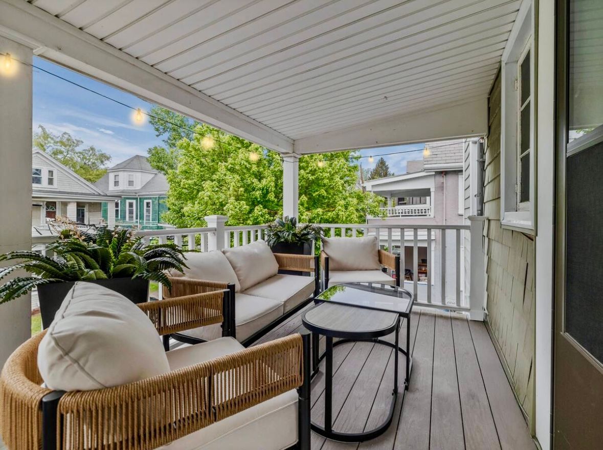 A cozy porch with wicker furniture, potted plants, and a small table.