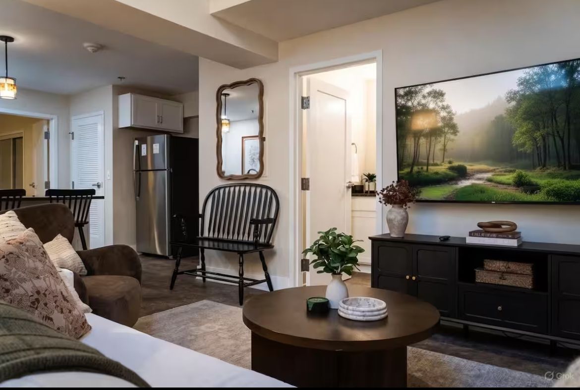 Living room with dark wood furniture, TV, and open doorway to a bathroom.