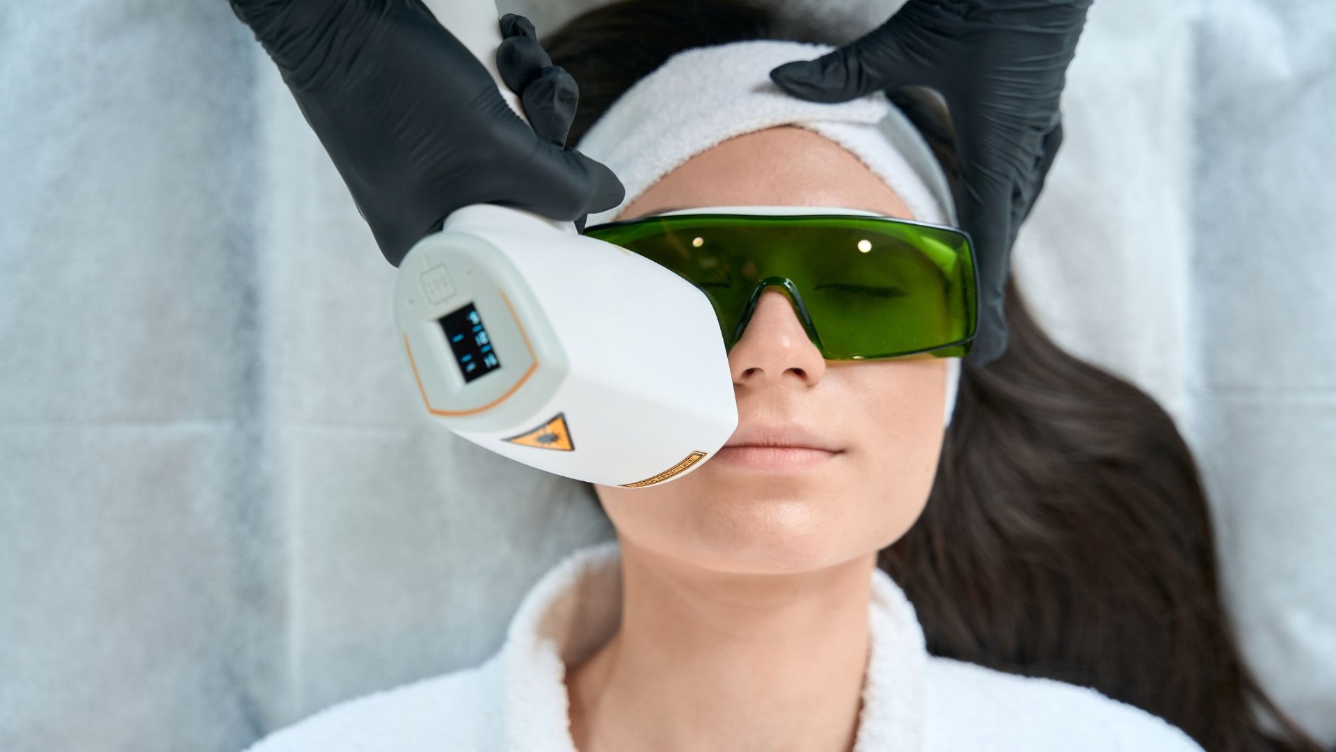 A woman is getting a laser hair removal treatment on her face.