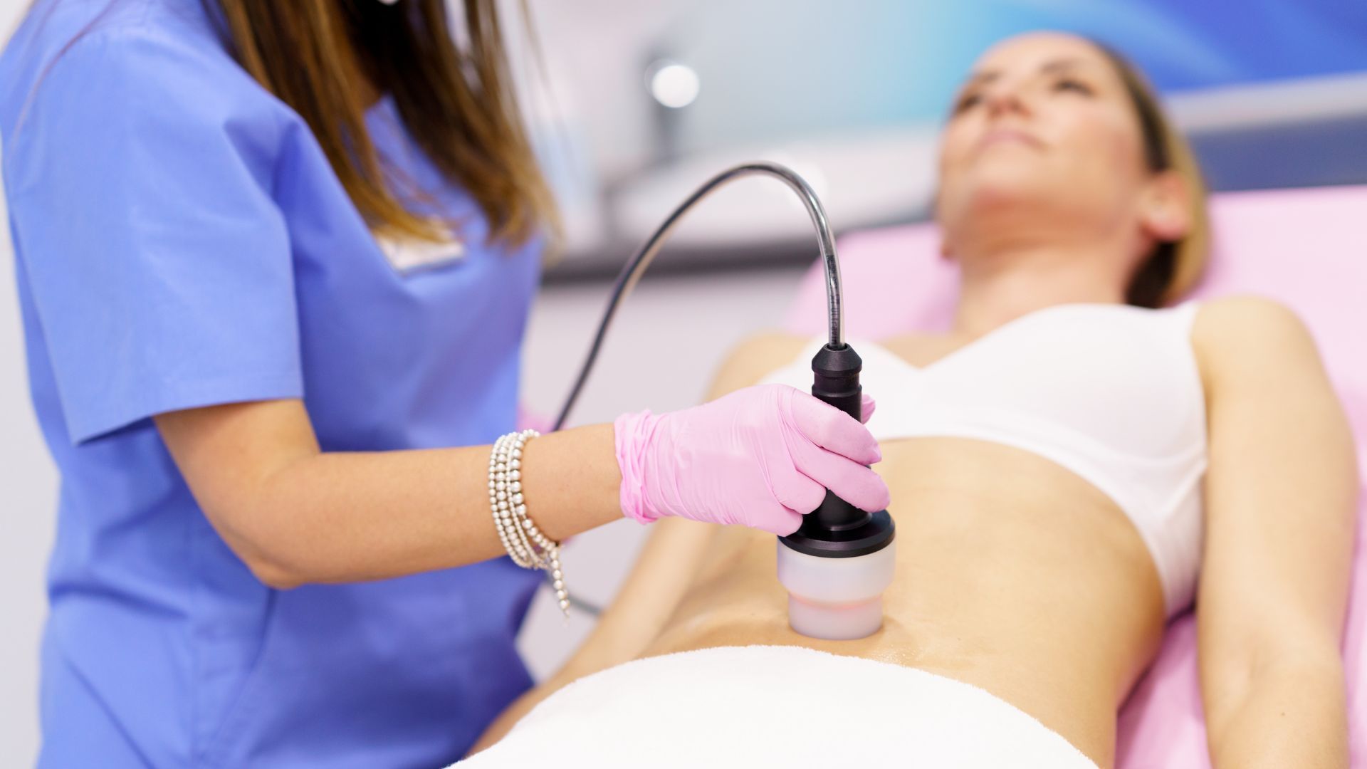 A woman is getting a cavitation treatment on her stomach.