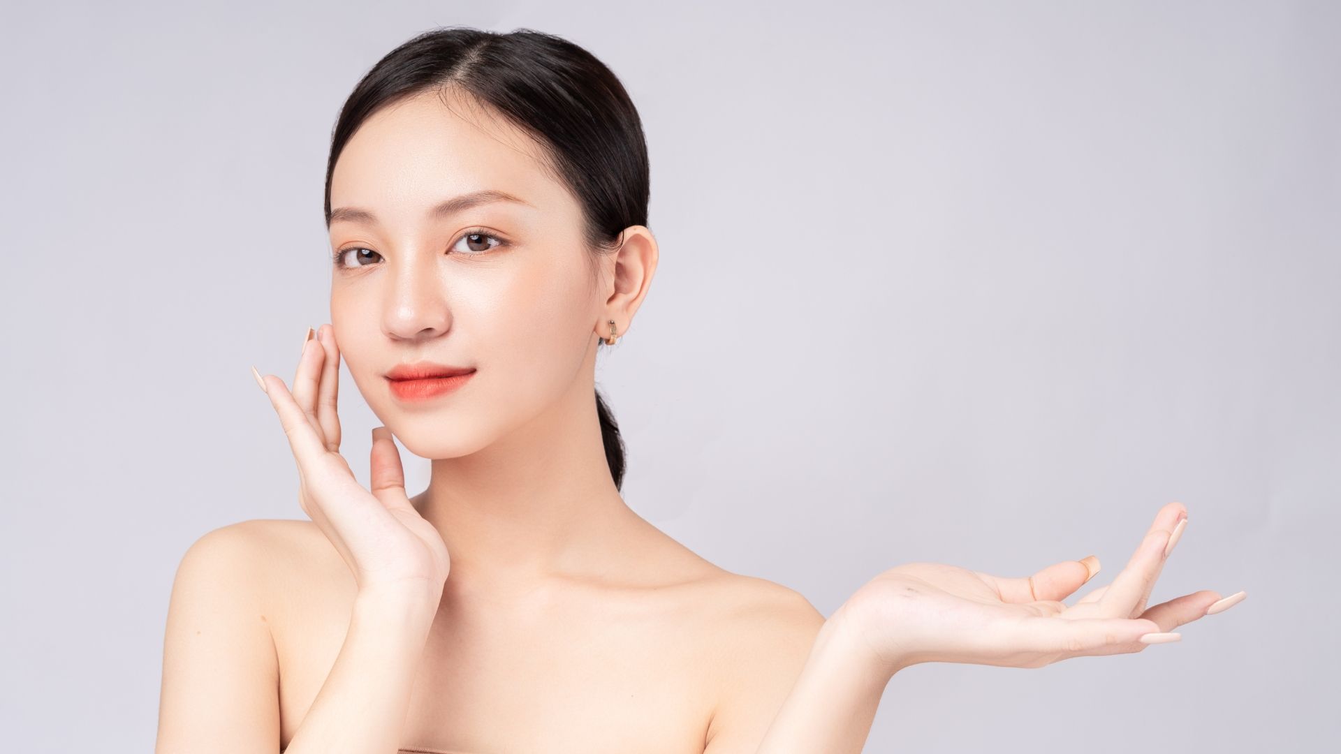 A woman is touching her face and holding her hand out.