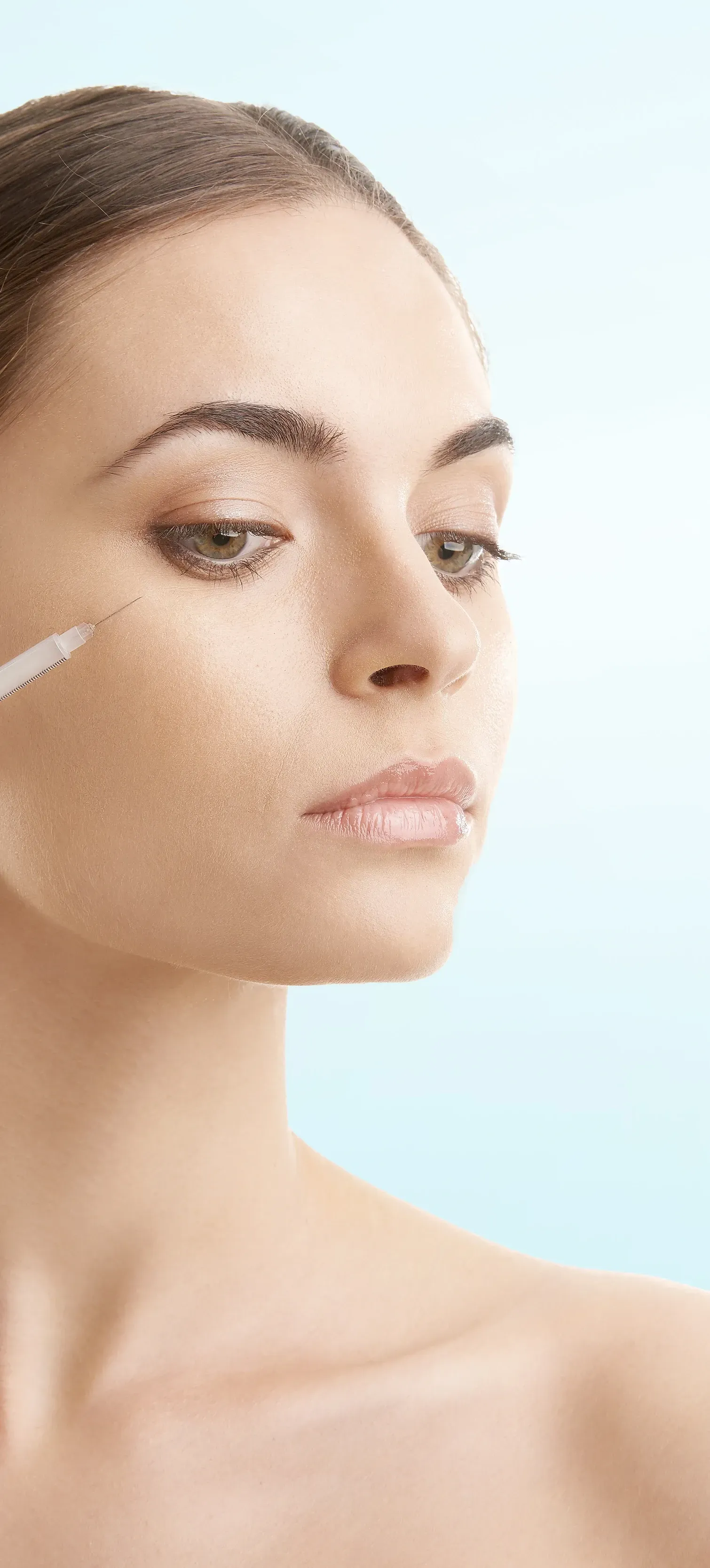 A woman is applying a serum to her face.