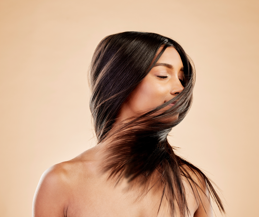 A woman with long hair is covering her face with her hair.