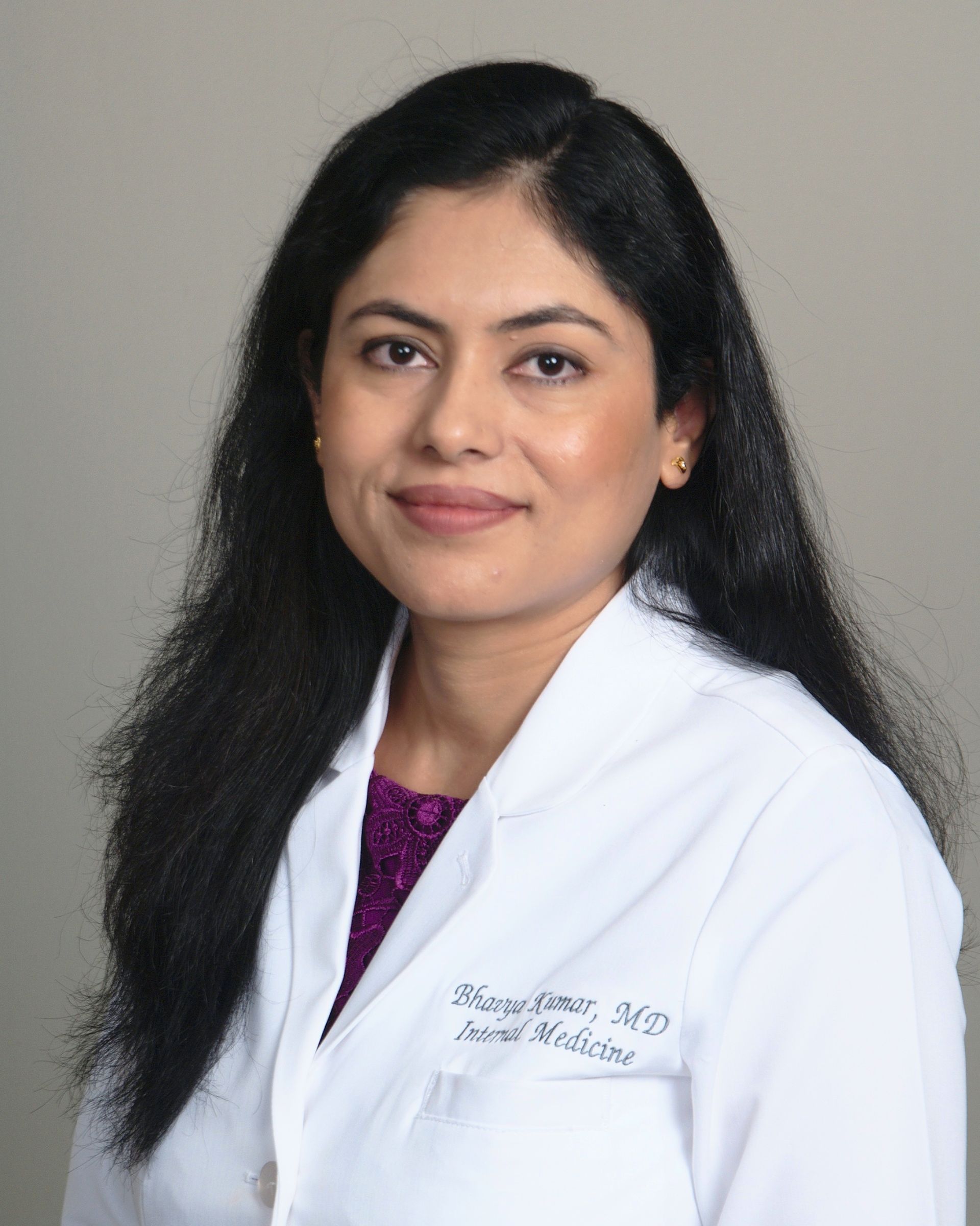 Woman in white lab coat, smiles. 