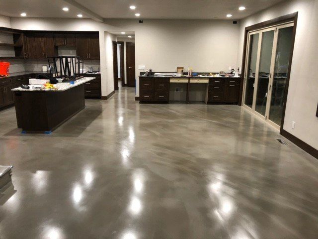 A kitchen with a shiny concrete floor and sliding glass doors.