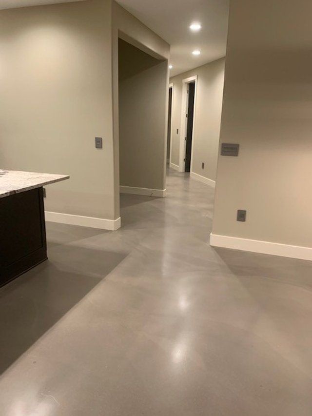 A hallway in a house with a gray floor and white walls.