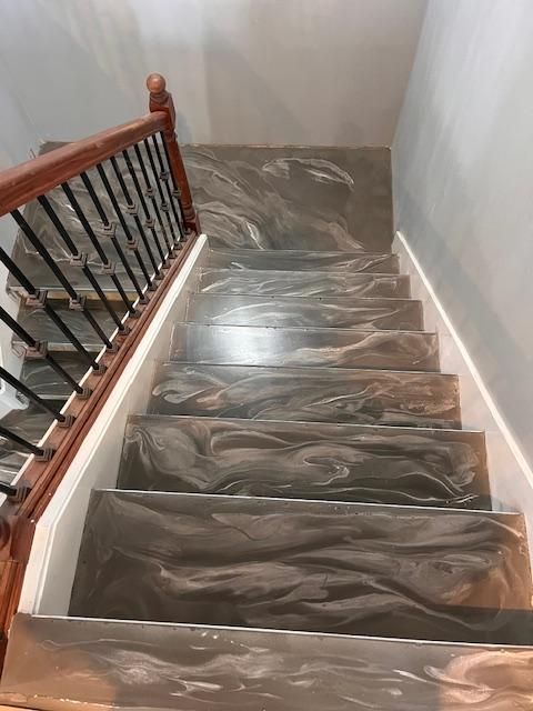 A set of stairs with a wooden railing and a marble floor.